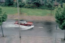 831076 Afbeelding van een auto die door de waterplassen heenrijdt in een ondergelopen Tigrisdreef te Utrecht.